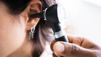 Doctor examining ear with otoscope